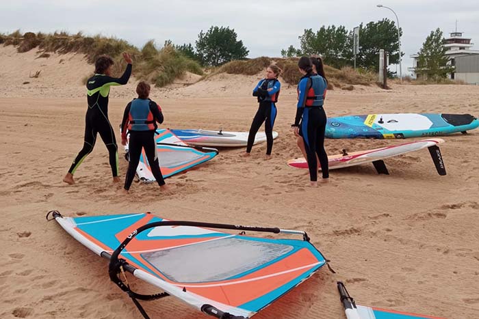 Varios niños atienden las explicaciones de un monitor de windsurf en la playa de Laredo (Cantabria)